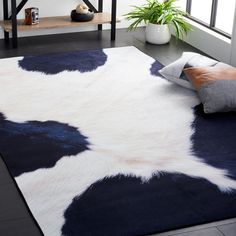 a cowhide rug is on the floor in front of a table with two vases