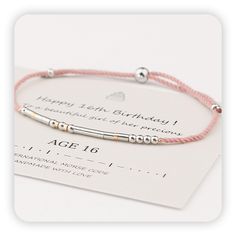 a pink cord bracelet with two silver beads and a happy 16th birthday message on it