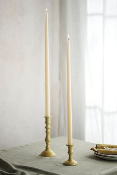 two candles are sitting on a table next to a plate