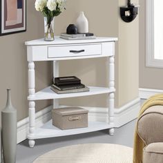 a white table with flowers and books on it in the corner of a living room