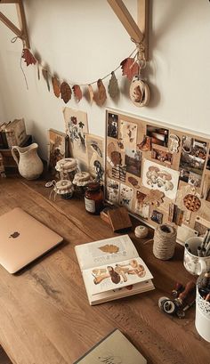 a wooden table topped with an open laptop computer next to pictures and other items on the wall