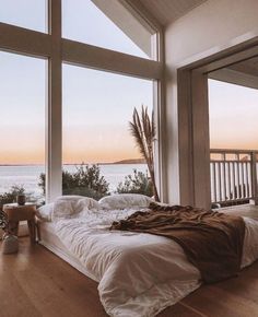 a bedroom with large windows and a bed on the floor next to an ocean view