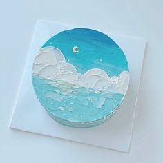 there is a blue cake with white frosting on the top that has an ocean scene painted on it