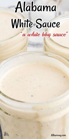 three jars filled with white sauce sitting on top of a table