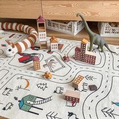 a toy dinosaur is on the floor next to some wooden blocks and toys in front of it