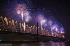 fireworks are lit up in the sky above a bridge