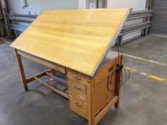 a wooden workbench with two drawers and an electrical outlet on the bottom shelf