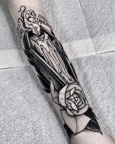 a black and white tattoo on the leg of a person with a rose in it