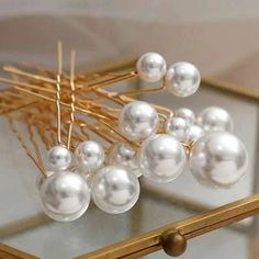 some white pearls and gold pins on a glass table