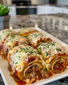 a white plate topped with lasagna rolls covered in cheese and sauce on top of a marble counter