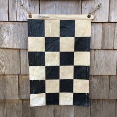 a black and white checkered towel hanging on a wooden wall next to a building