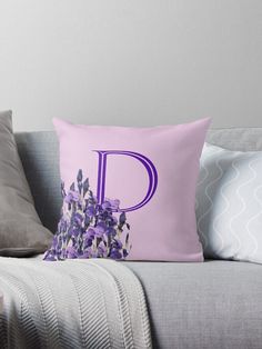 the letter d is made up of purple flowers on a gray couch with grey pillows