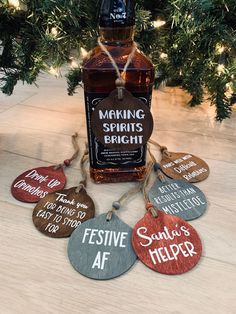 a bottle of alcohol sitting on top of a wooden table next to some tags that say making spirits bright