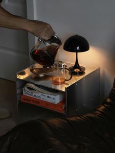 a person pours coffee into a glass cup on top of a stack of books