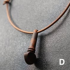 a necklace with a wooden bead hanging from it's side on a gray surface