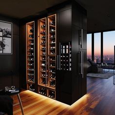 a wine cellar in the middle of a living room with hardwood floors and large windows