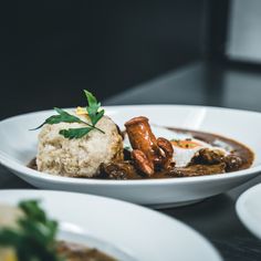 a white bowl filled with food on top of a table next to other plates and utensils