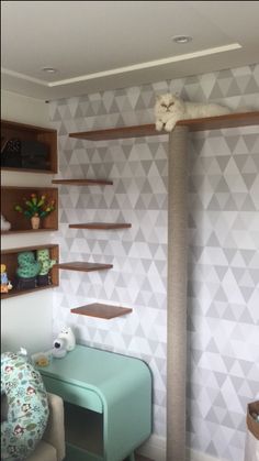 a cat sitting on top of a scratching post in a room with geometric wallpaper