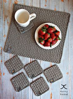 a bowl of strawberries next to coasters on a table