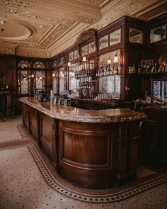 an elegant bar with wooden cabinets and marble counter tops