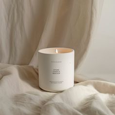 a white candle sitting on top of a bed