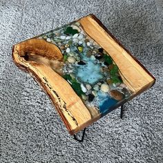 a table made out of wood and glass with rocks on the bottom, sitting on carpeted area