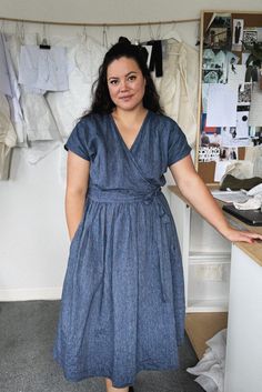 a woman in a blue dress standing next to a counter