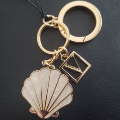 a keychain with a shell charm hanging from it's side on a black surface