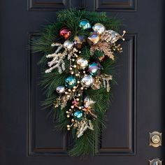 a christmas wreath is hanging on the front door with ornaments and greenery around it