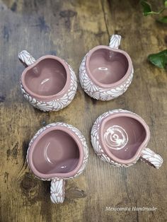 three pink ceramic teapots sitting on top of a wooden table