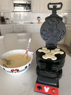 a mickey mouse waffle maker and bowl of batter