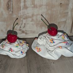 two plastic cherries sitting on top of white cloth