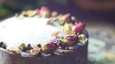 a close up of a cake on a plate with frosting and rose petals around it