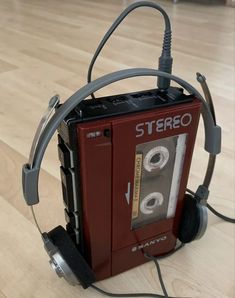 an old stereo with headphones attached to it sitting on the floor in front of a wooden floor