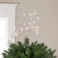 a christmas ornament with lights on top of a pine tree in a vase