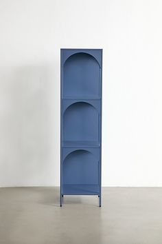 a tall blue shelf sitting on top of a cement floor next to a white wall