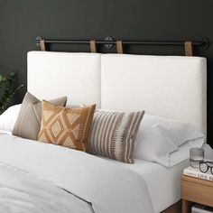 a bed with white linens and pillows on it