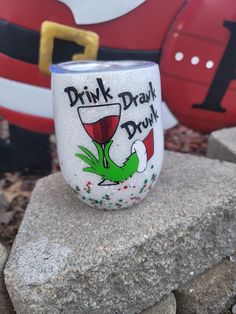 a wine glass sitting on top of a rock next to a santa clause figure in the background