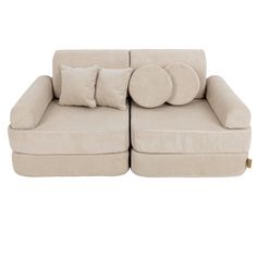 a large beige couch with pillows on it's back and two smaller ones sitting next to each other