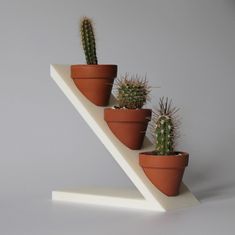 three potted plants are sitting on a shelf in the shape of a zigzag