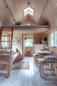 the interior of a tiny cabin with wooden walls and ceilings, wood flooring, ladders to the loft