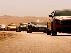 a group of cars driving down a desert road