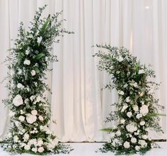 two tall white flowers and greenery are on display