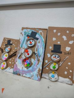 three cardboard boxes with snowmen painted on them and some paintbrushes in front of them