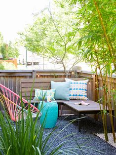 an outdoor seating area with bamboo trees and other plants in the back yard, along with potted grass