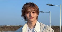 a young man wearing a white shirt and tie standing in front of street lights on a sunny day