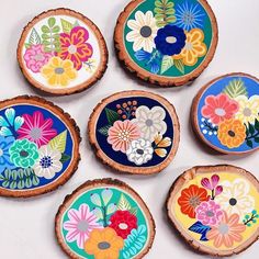 six painted wood slices with flowers on them sitting next to each other in front of a white background