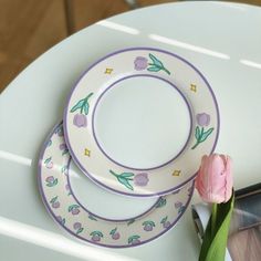 three plates with flowers on them are sitting on a table next to an empty vase