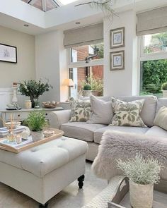 a living room filled with lots of furniture next to a window covered in plants and potted plants