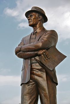 a statue of a man in a suit and hat with his arms crossed, looking to the side